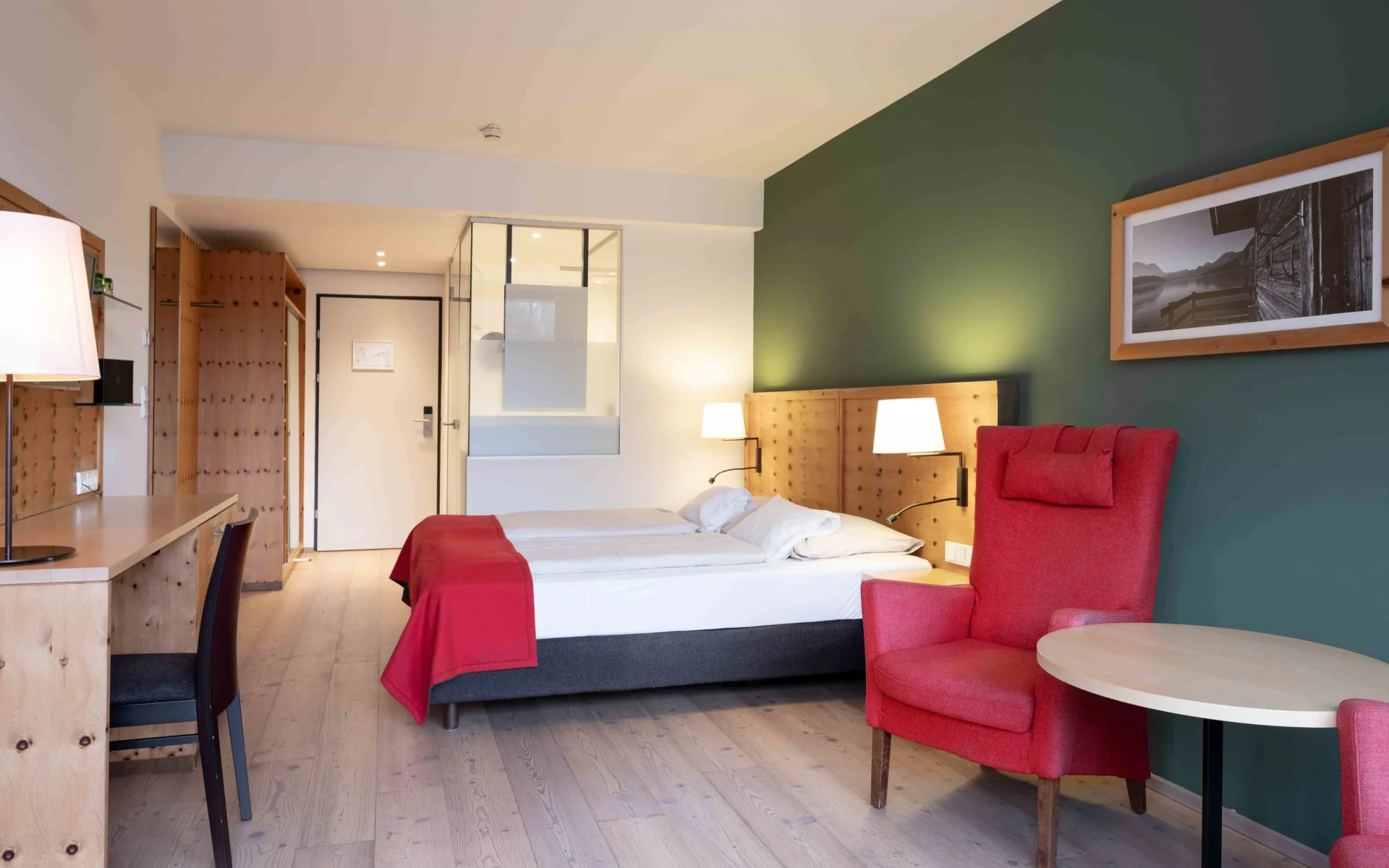 Blick in ein Zimmer im Hotel Erzherzog Johann mit Ohrensessel, Doppelbett und Schreibtisch.