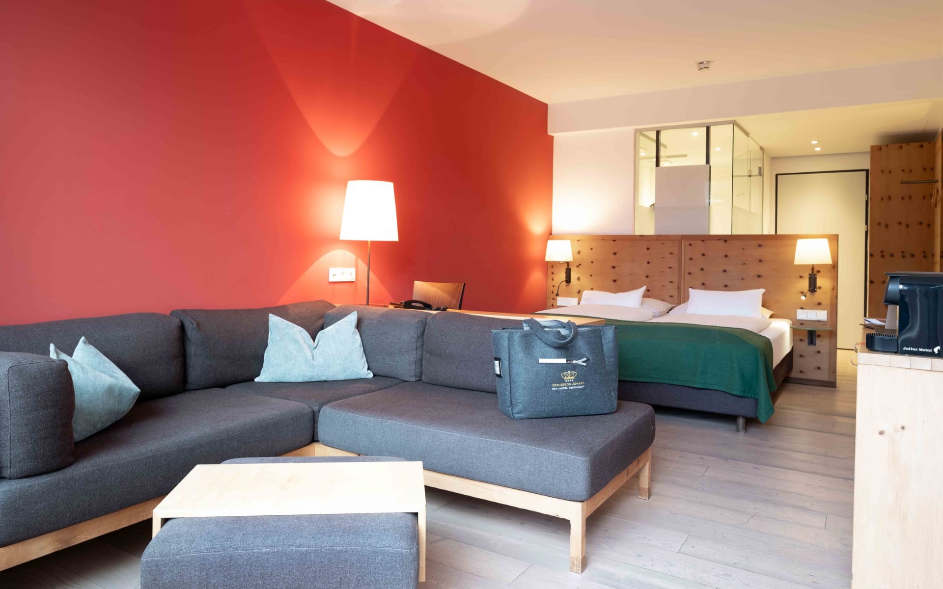 Blick in ein Hotelzimmer mit Sofa, Doppelbett und Kaffeemaschine im Vordergrund.