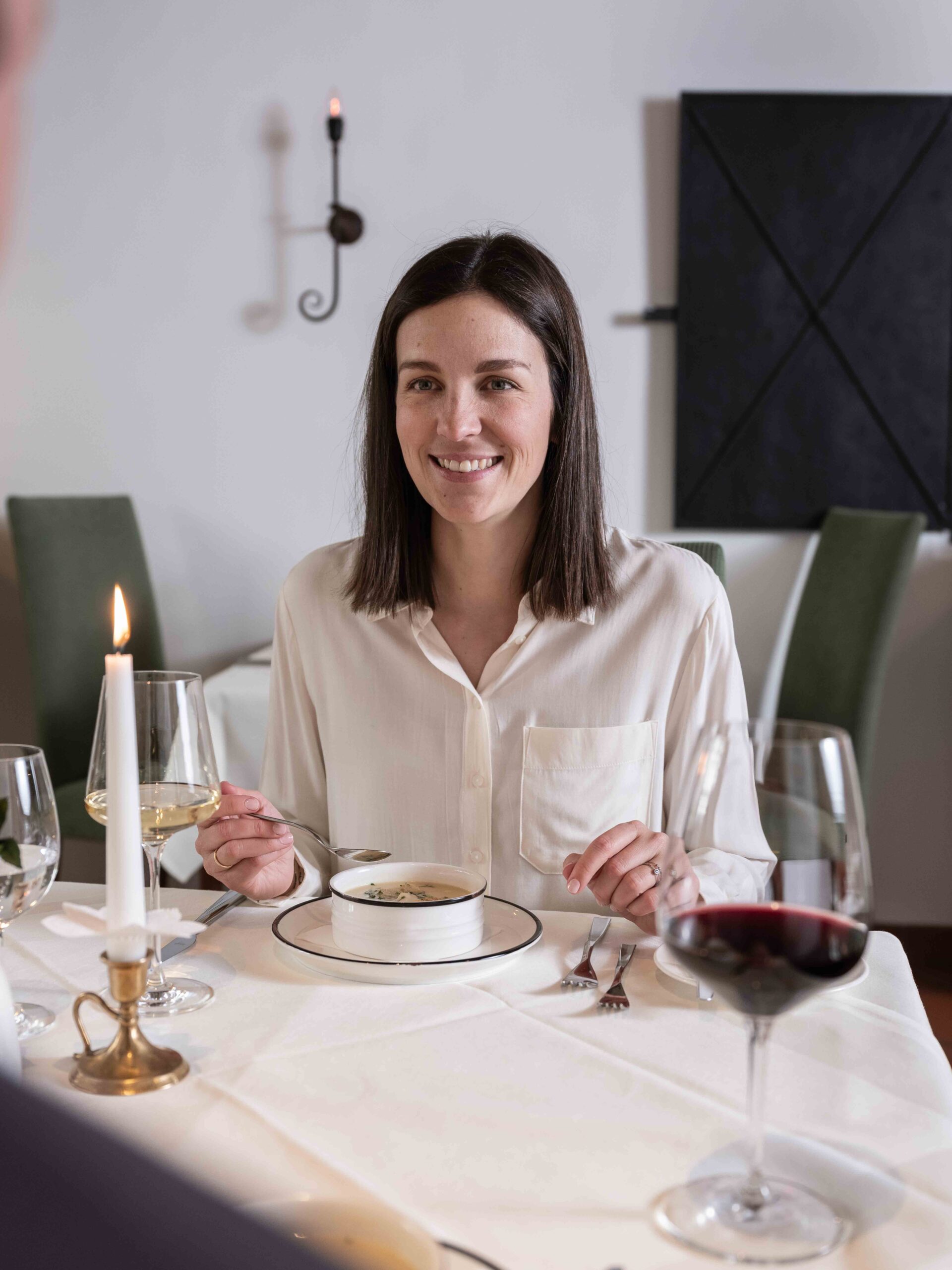 Eine Frau beim Abendessen mit einer Fritattensuppe.