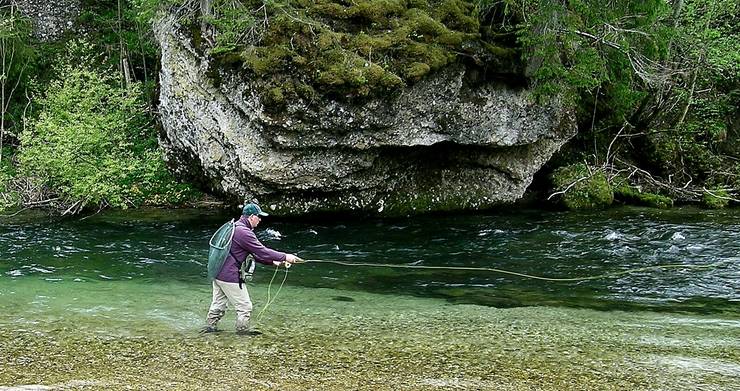 Ein Fischer im Fluss mit einer Angel.