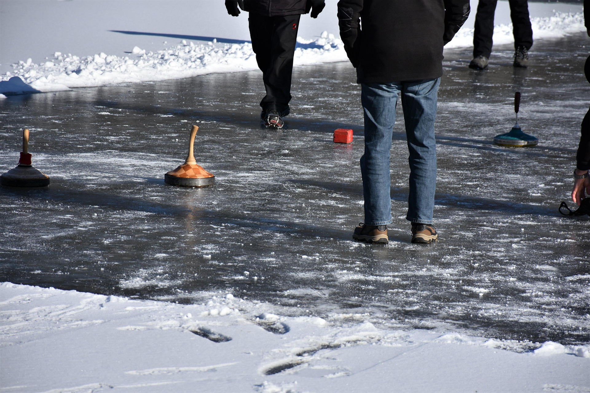 Mehrere Personen am Eis beim Eisstockschießen.