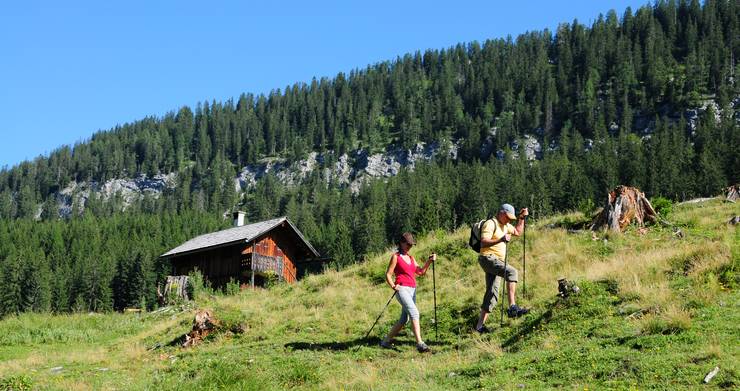 Wanderer auf der Alm, im Hintergrund ein kleines Almhaus.